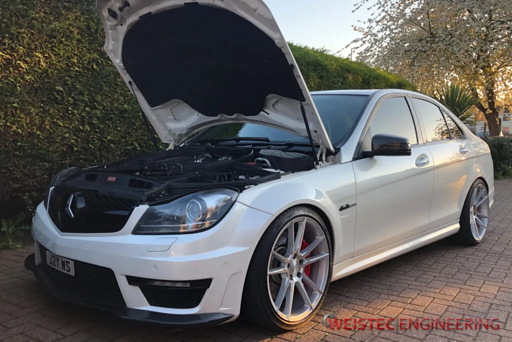 A white car with its hood open and the engine bay.